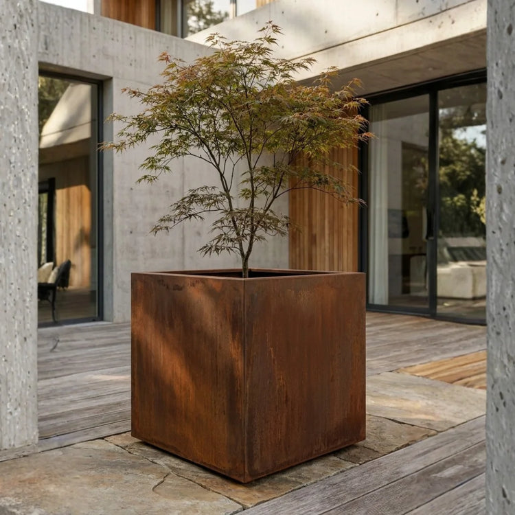 Steelart CUBE kubo formos metalinis lauko vazonas natūralios plieno spalvos prie modernaus namo terasos